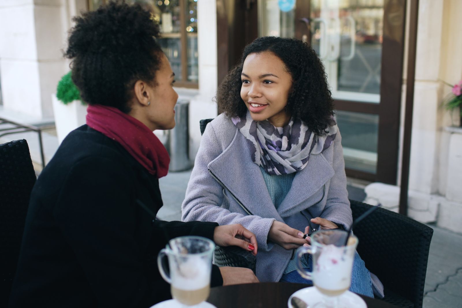 Deux jeunes femmes discutent en souriant à la terrasse d'un café